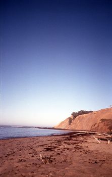 Captivating view of the California coast with cliffs and ocean waves at sunset.