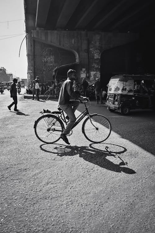 A black and white photo of a man riding a bike