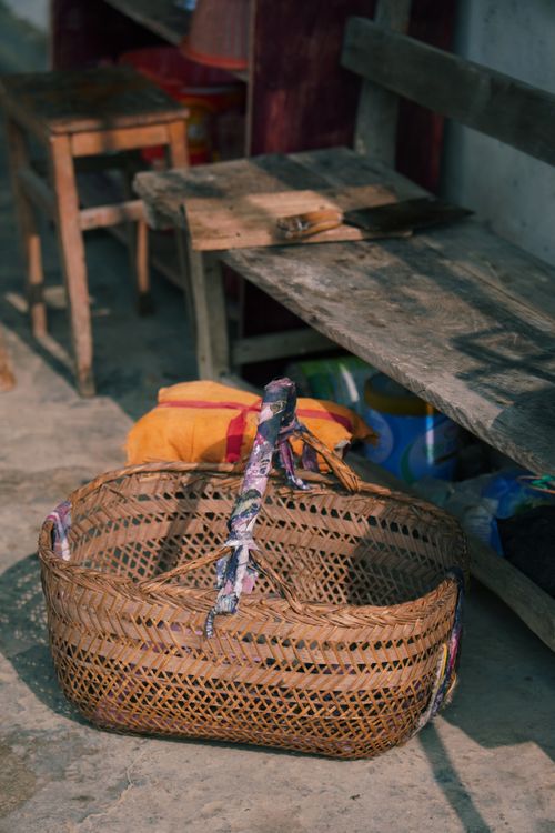 Free A rustic woven basket placed on a stone floor in a rural setting, offering a glimpse into traditional life. Stock Photo