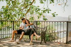 A couple embraces on a park bench under a tree, capturing a serene and romantic moment.