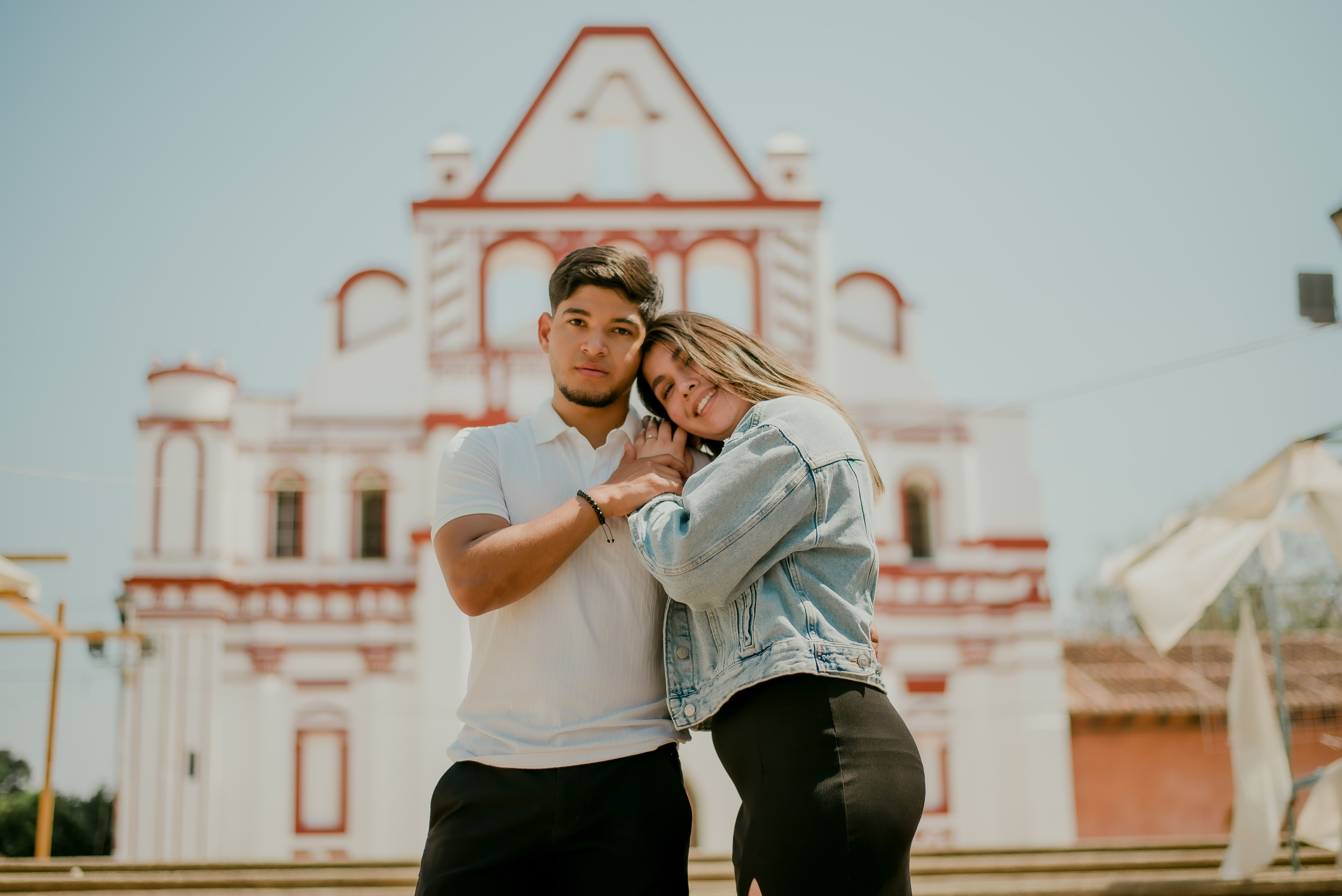 A young couple embracing romantically in front of a historical building, symbolizing love.