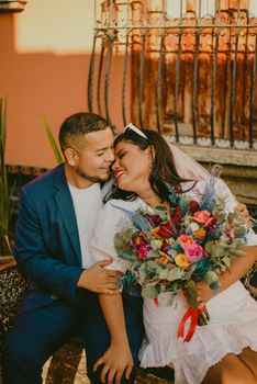 Happy bride and groom sharing a joyful moment with vibrant bouquet.