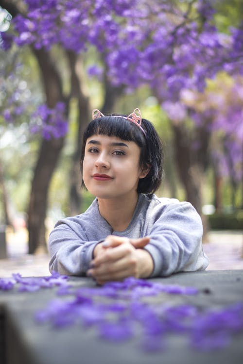 A young woman sitting on a bench with purple flowers