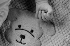 Black and white photo of a baby's hand wearing a bracelet on a textured dog blanket.