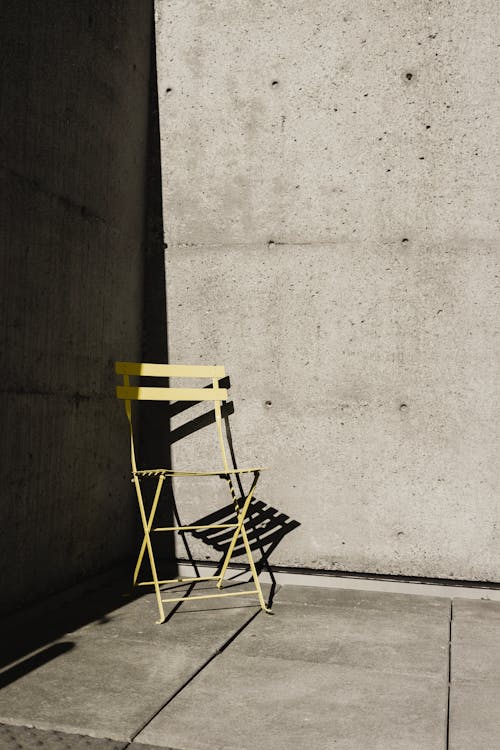 A yellow chair sits in front of a concrete wall