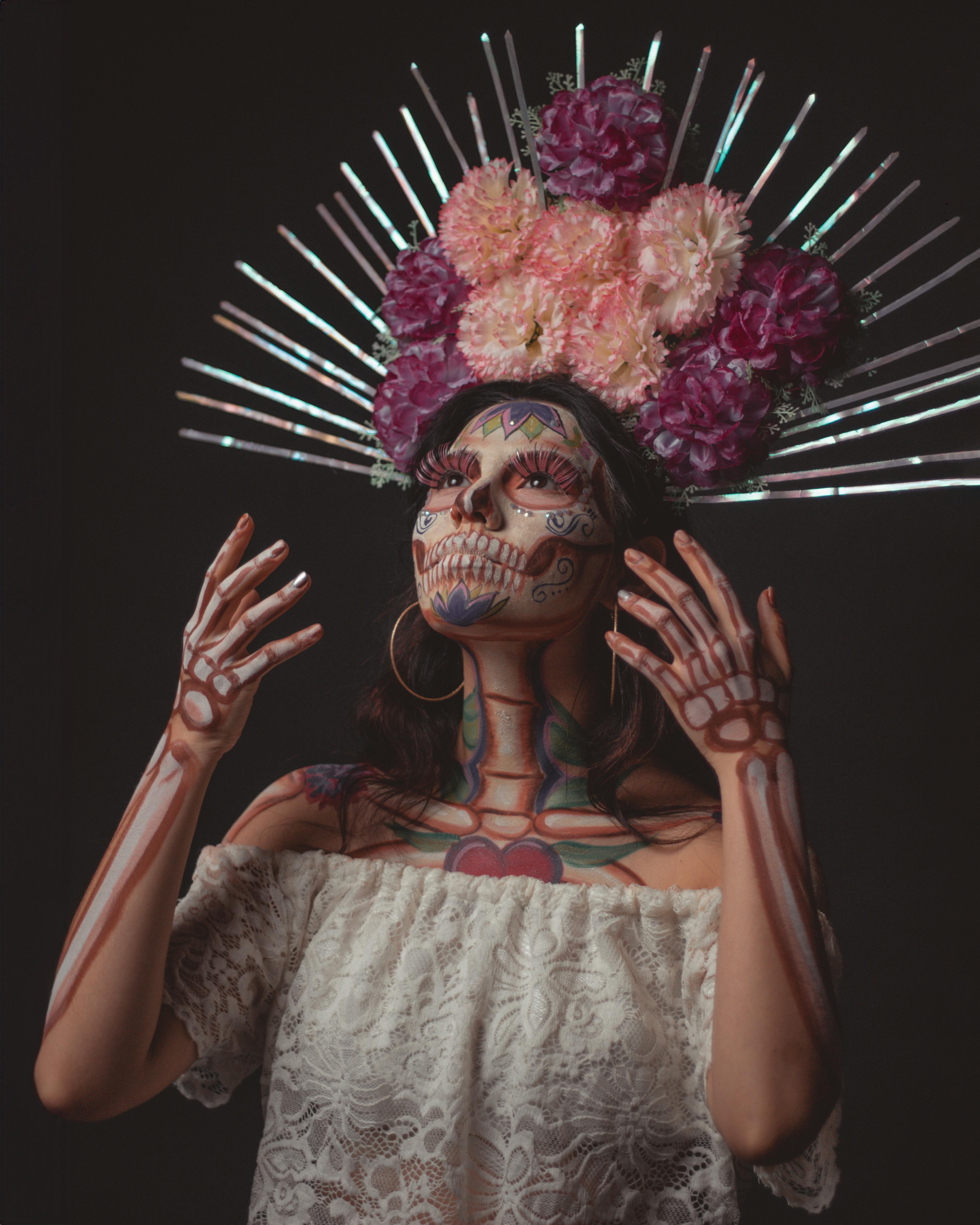 woman in catrina makeup wearing headdresss with flowers