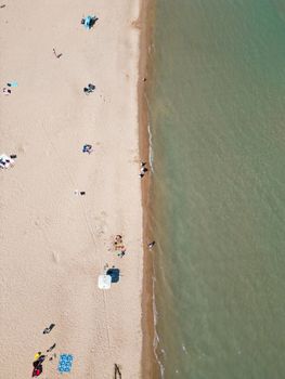 Drone shot of a serene beach in Evanston, IL, with sunbathers and gentle waves.