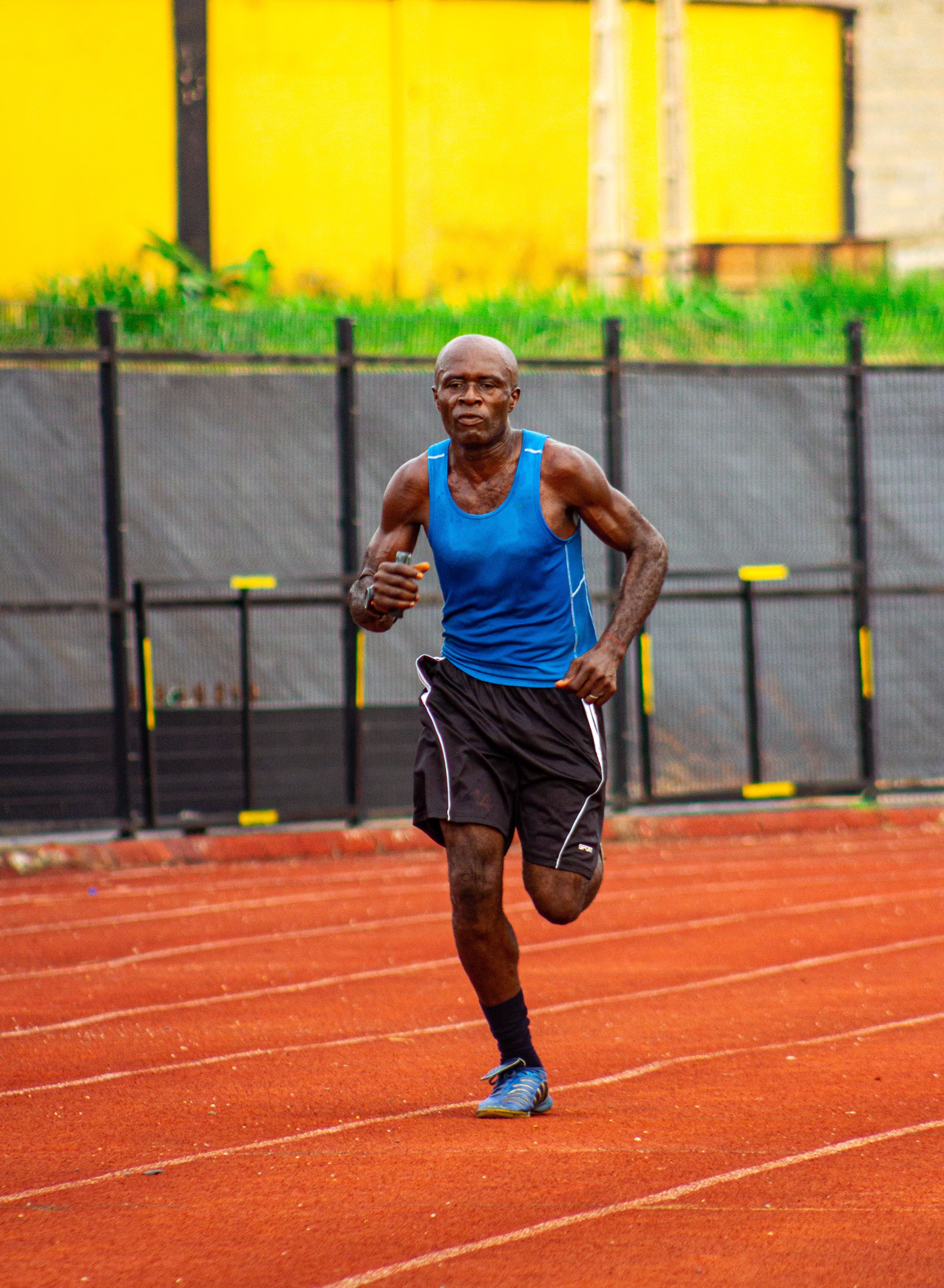 Fit African American man in blue running on an outdoor track. Health and fitness lifestyle.