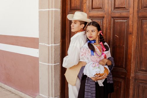 Free Two people in traditional Mexican costumes standing back to back against a wooden door in Puebla, Mexico. Stock Photo