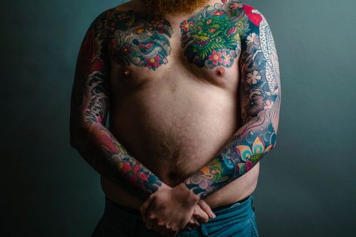 Free Portrait of a shirtless man with vibrant tattoos on chest and arms. Stock Photo