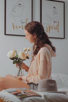 A young woman admiring white roses in a stylish Parisian apartment, showcasing a calm interior setting.