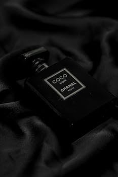 Luxurious close-up of a Chanel Coco Noir perfume bottle on black fabric, emphasizing elegance.