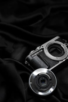 Artistic shot of an Olympus PEN camera and lens on black fabric. Ideal for photography enthusiasts.