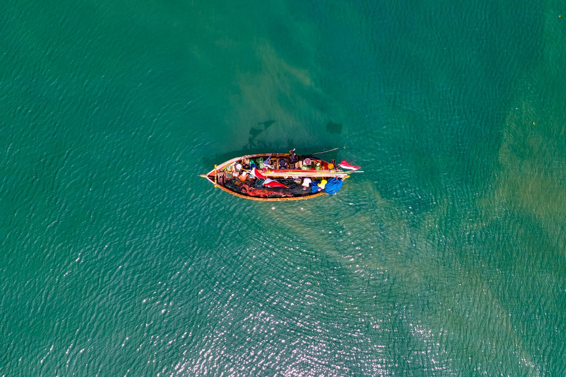 Top-down drone shot of a fishing boat navigating tropical waters near Banten, Indonesia.