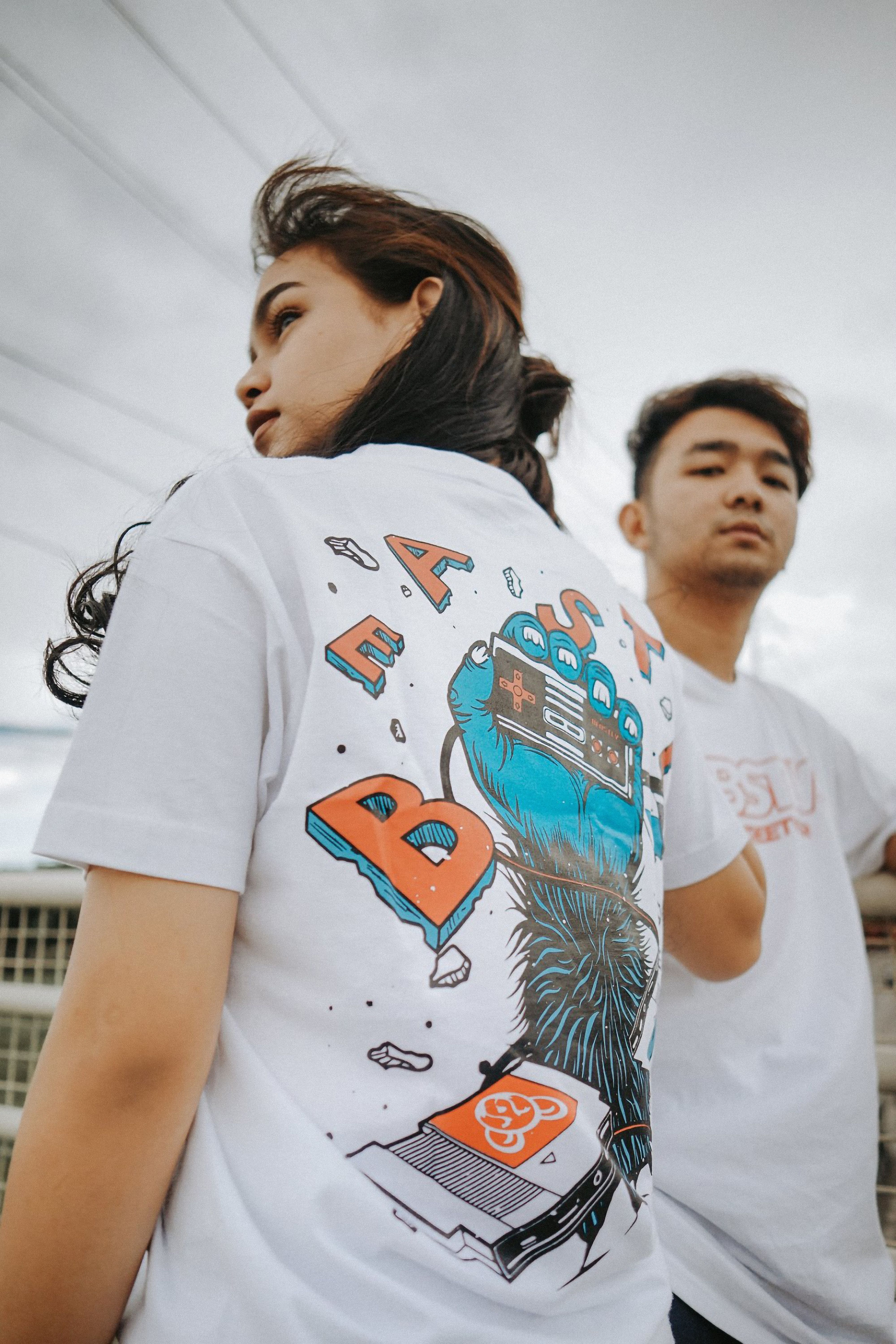 Stylish portrait of young Asian models posing in trendy T-shirts outdoors.