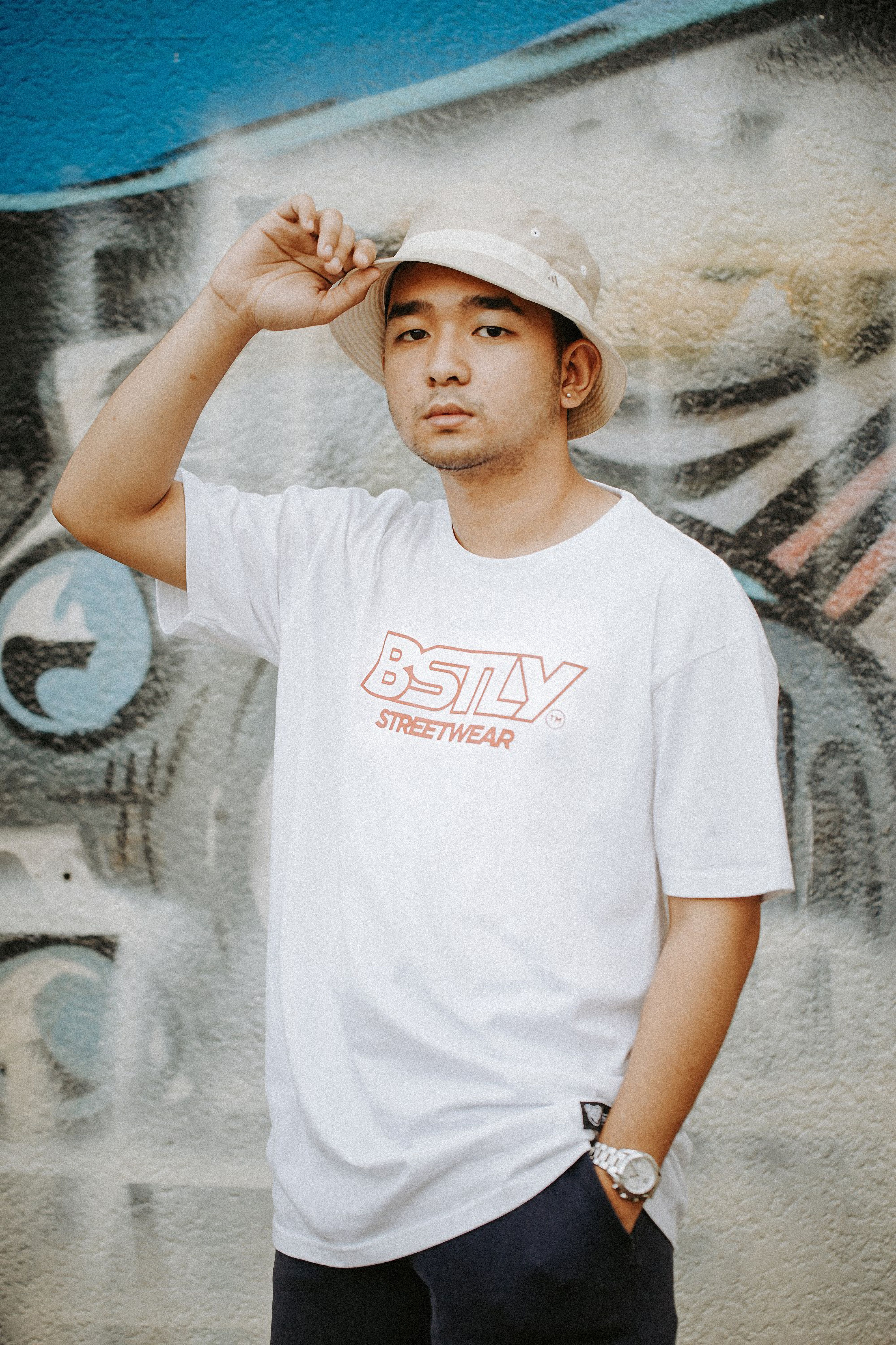 Young man in casual streetwear poses confidently against a vibrant graffiti wall, showcasing modern fashion.