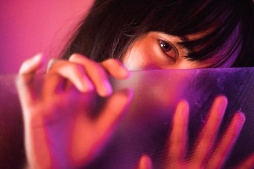 Free Artistic close-up portrait of a woman behind frosted glass with vibrant pink lighting. Stock Photo