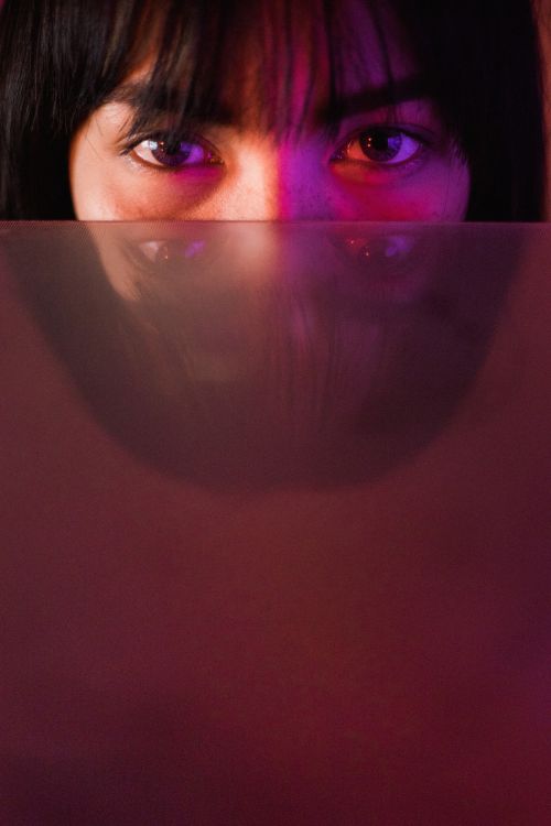 Free Close-up artistic portrait with striking pink and purple lighting and reflection effect. Stock Photo