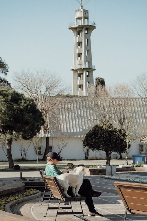 A woman sitting on a bench in front of a clock tower