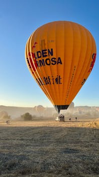A vibrant orange hot air balloon ready to take off in Cappadocia, Türkiye.