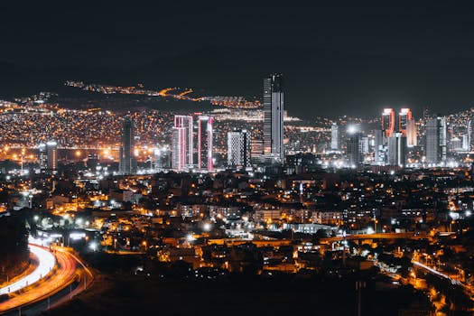 Vibrant nighttime cityscape of İzmir, Türkiye featuring illuminated skyscrapers and urban lights.