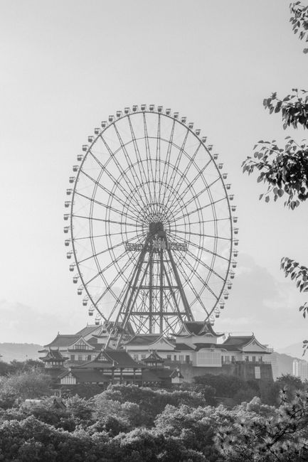 Black and white photo of a Ferris wheel against a skyline, exuding nostalgic charm.