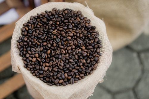 Free A detailed view of roasted coffee beans in a burlap sack, showing texture and color. Stock Photo