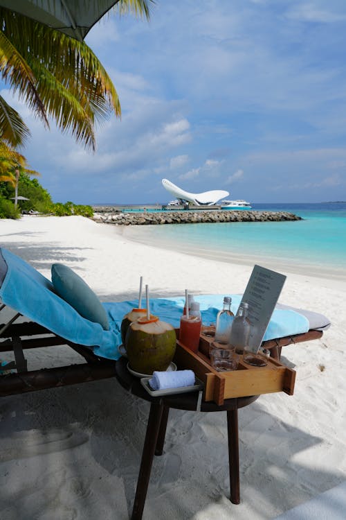 A beach lounge with a table and drinks on it