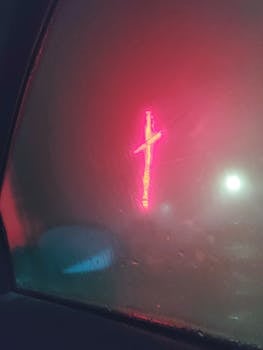 透过雾蒙蒙的车窗，模糊的霓虹灯红十字会闪耀着，营造出喜怒无常的夜景