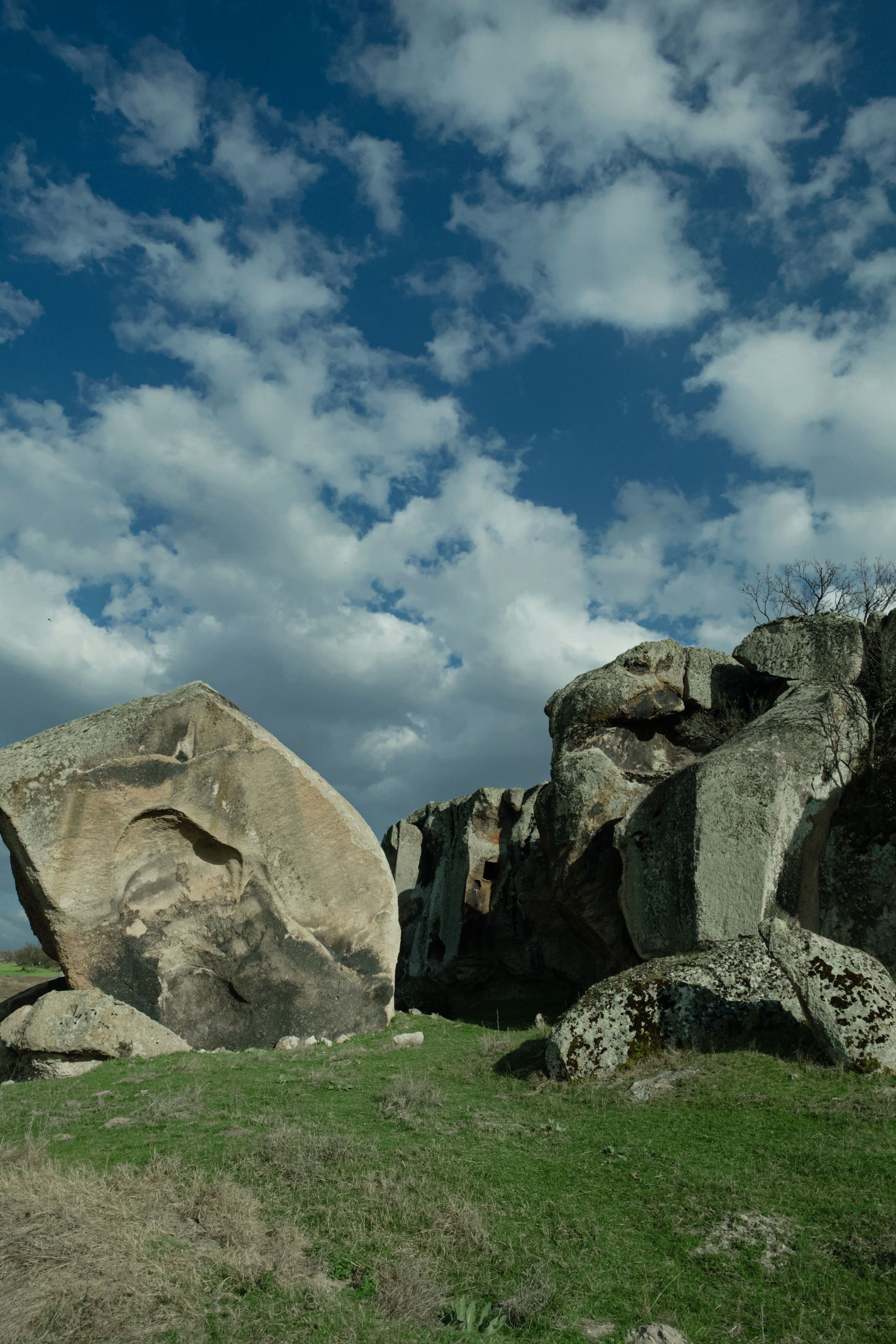 A large rock formation in the middle of a grassy field · Free Stock Photo