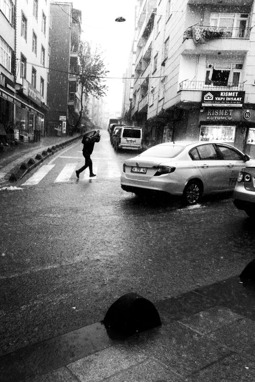 Free A person crossing a wet street in Istanbul during rain, showcasing urban life. Stock Photo