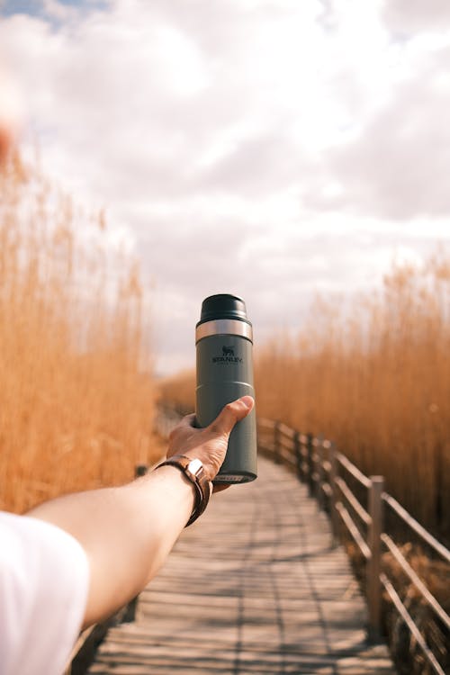 A person holding a water bottle on a wooden walkway