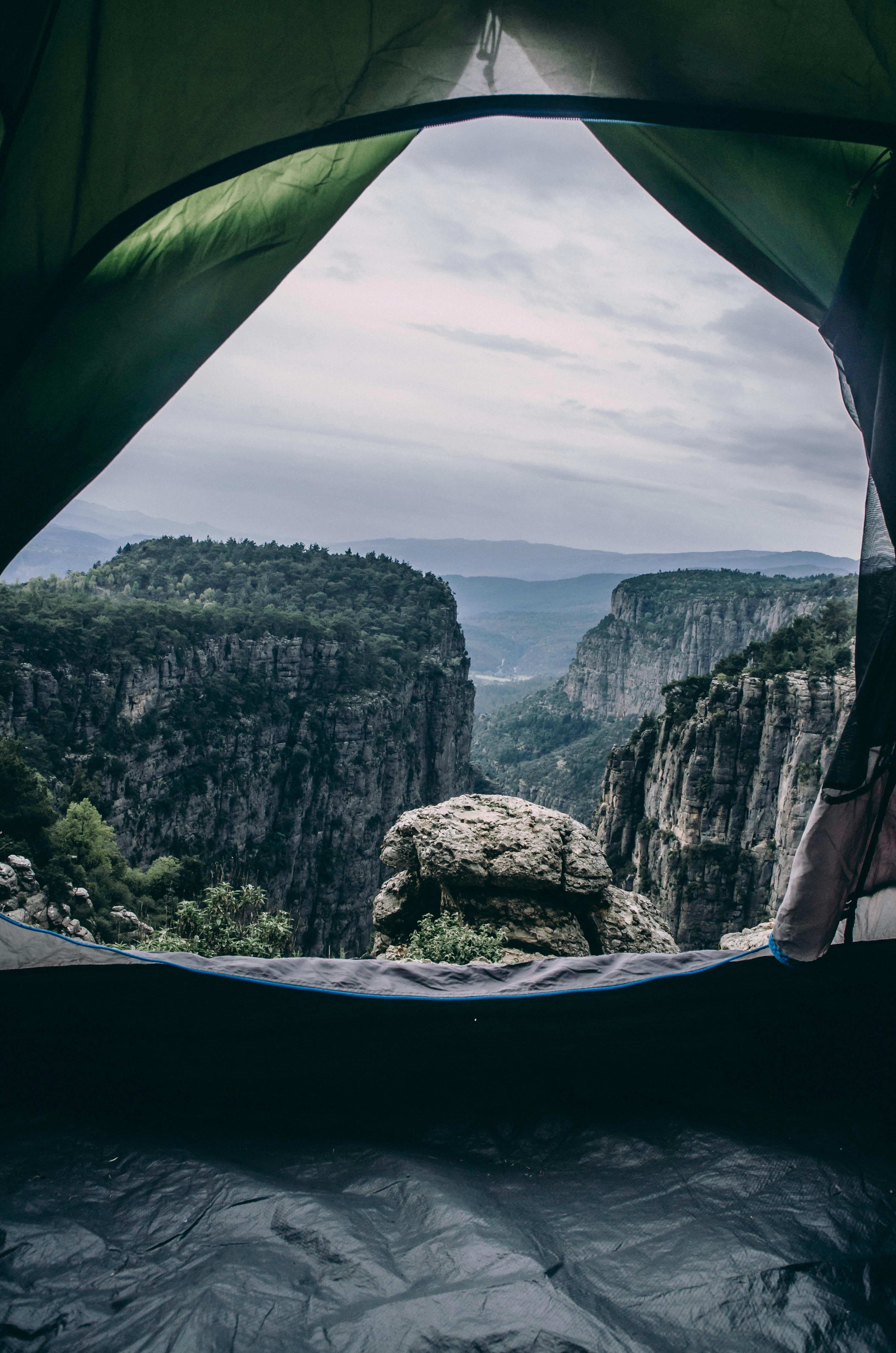 person inside dome tent on cliff