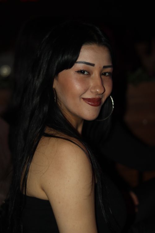 Free Portrait of a stylish woman with long hair smiling at a nighttime event. Stock Photo