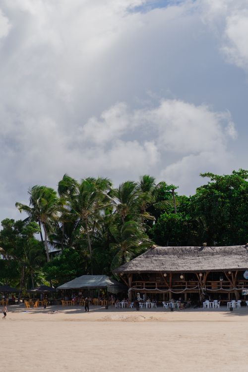 Free A scenic tropical beach with a tiki hut and palm trees, perfect for leisure and relaxation. Stock Photo