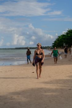 People walking along a tropical beach on a sunny day, enjoying leisure time by the ocean.