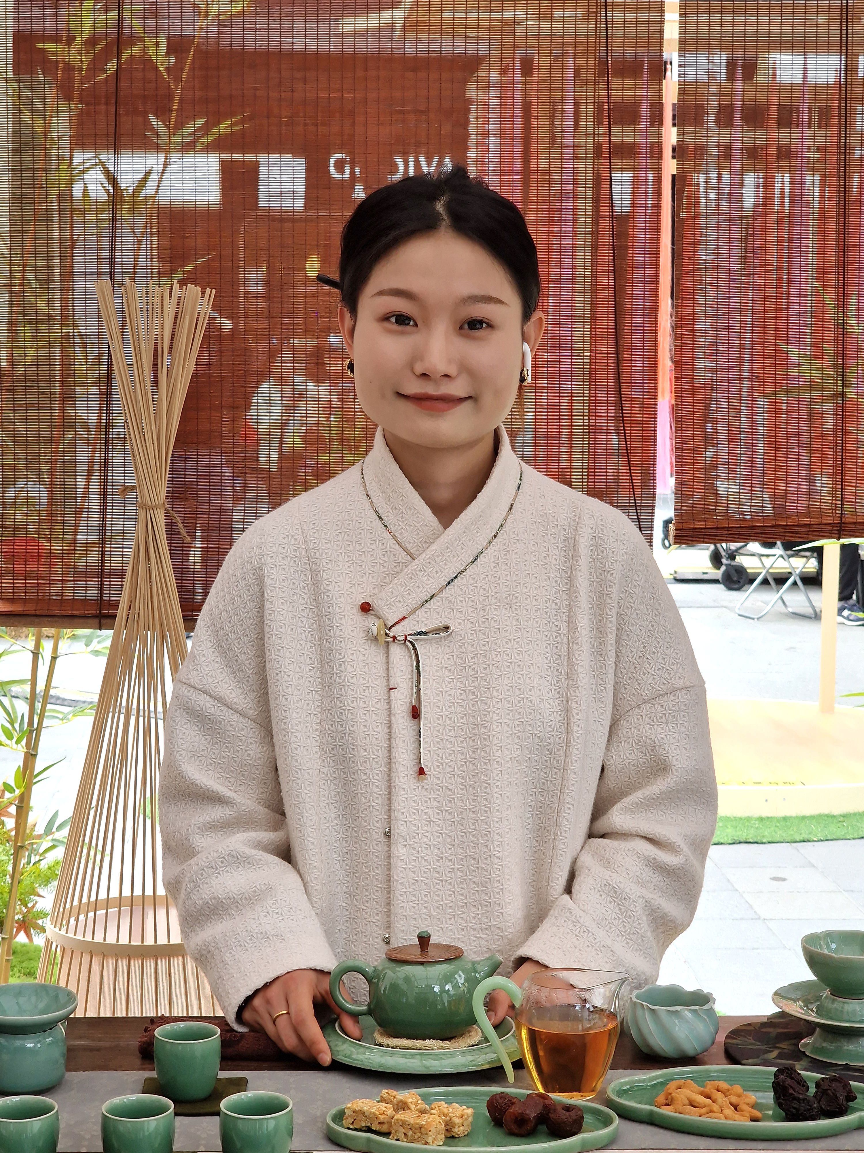 Smiling Asian woman in traditional attire serving tea, showcasing cultural heritage.