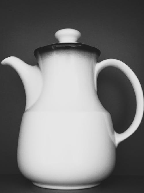 A black and white photo of a white teapot