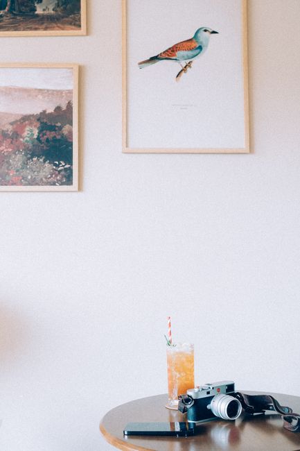 A cozy indoor setting with framed art, a vintage camera, and a refreshing drink on a table.