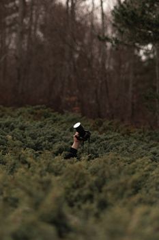 A person holding a camera amidst dense forest bushes, creating a mysterious scene.
