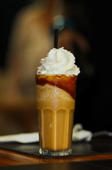 Indulge in a creamy iced coffee topped with whipped cream, captured in a perfect vertical shot.