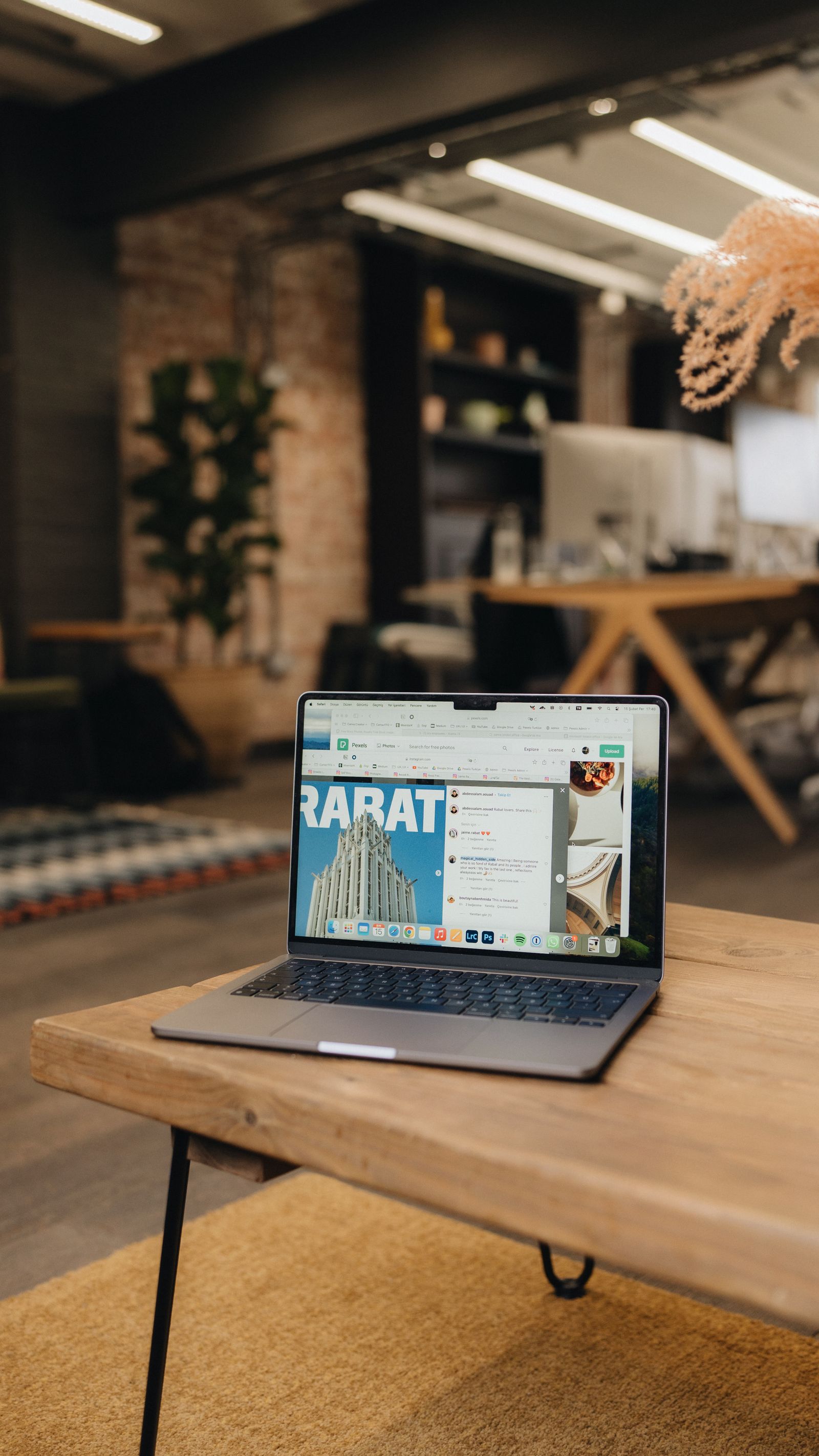 Laptop open on a wooden table in a bright open office