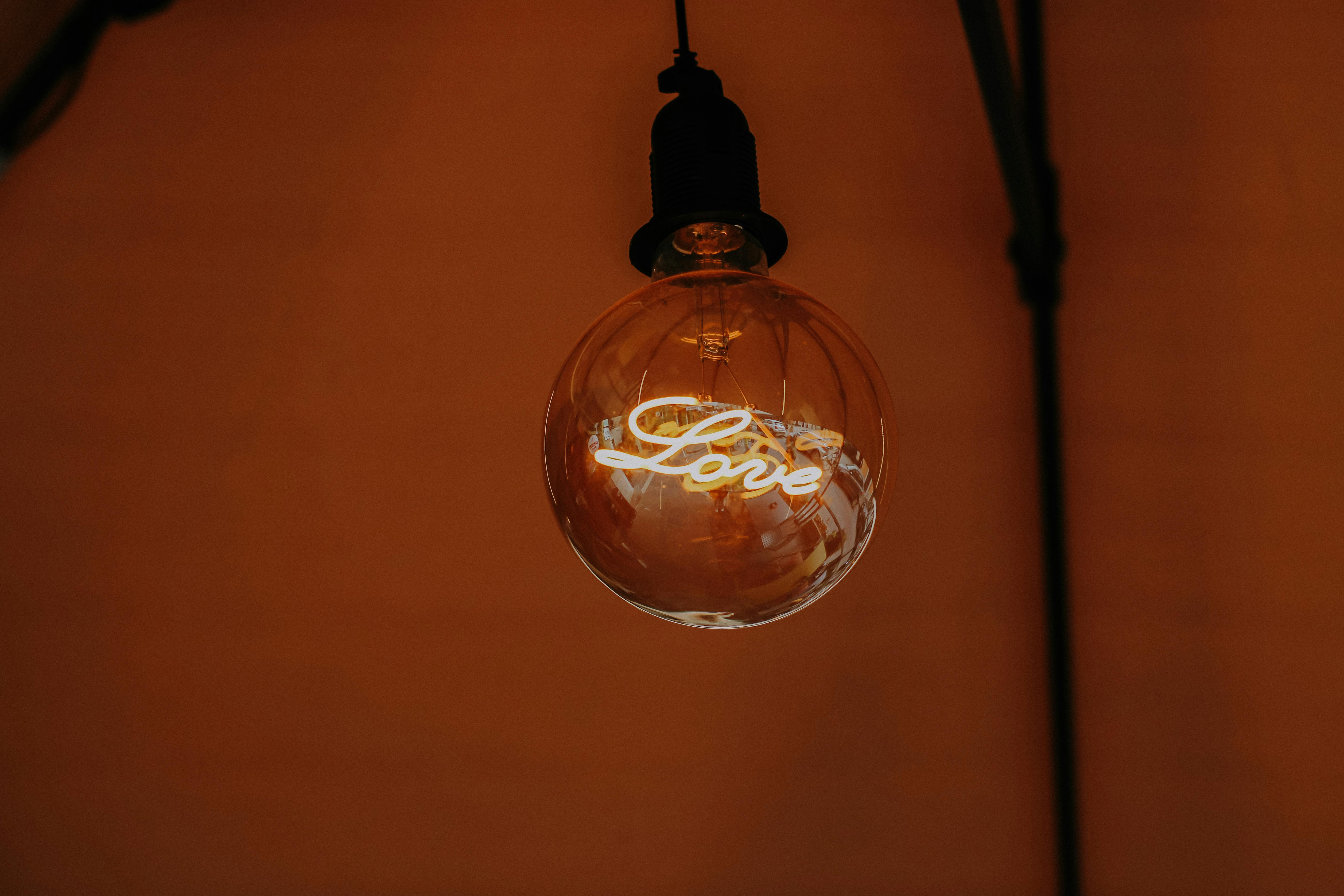 Close-up of a glowing vintage light bulb displaying the word 'Love'.