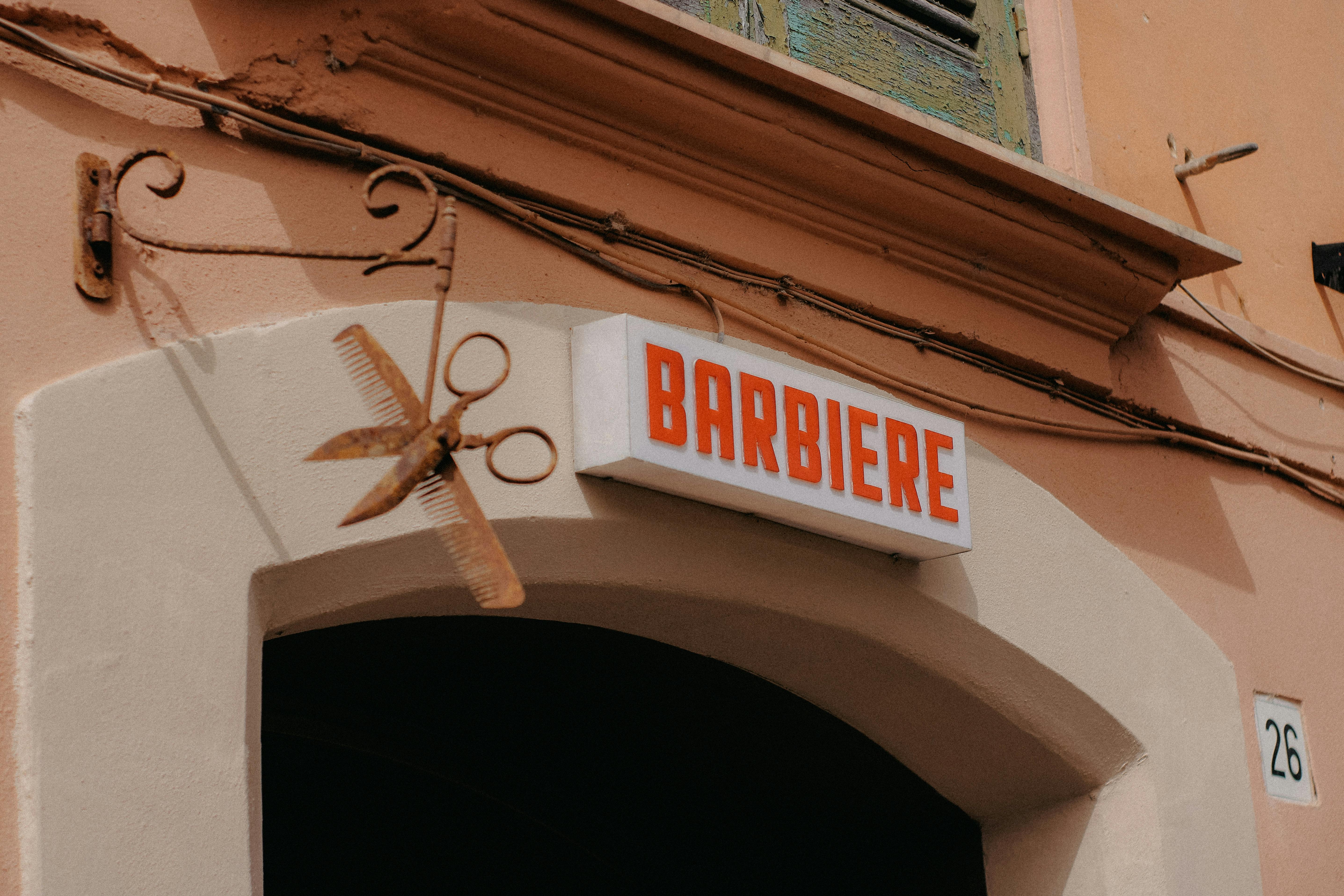Rustic barber shop sign with vintage scissors on an urban wall in a European street.