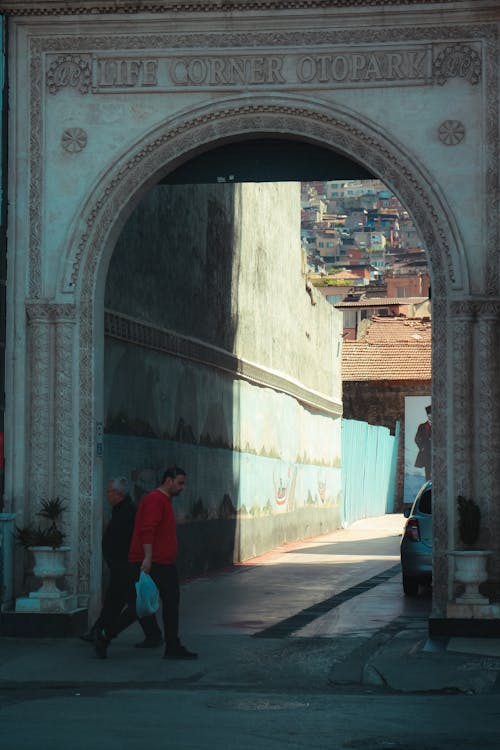 A man walking through an archway in a city