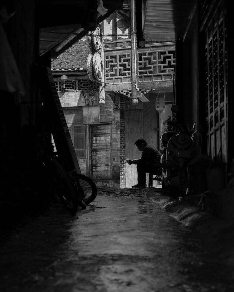 Man Sitting On Chair By House In City