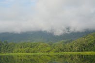 探索马来西亚怡保雾气缭绕的宁静山地景观，绿树成荫，倒影盎然