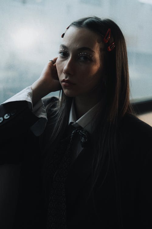 A woman in a suit and tie is looking out the window