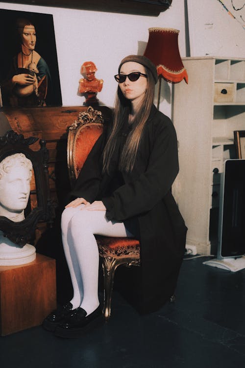 Woman Sitting in Black Clothes, Hat and Sunglasses