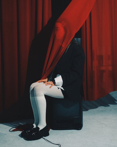 Woman Sitting behind Red Curtain
